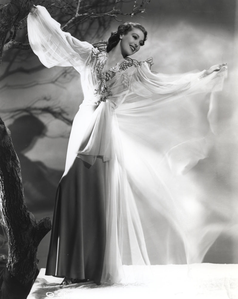 Loretta Young in a white long dress standing by a dead tree - photo print