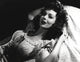 Loretta Young lying in bed photo print with curly hair.