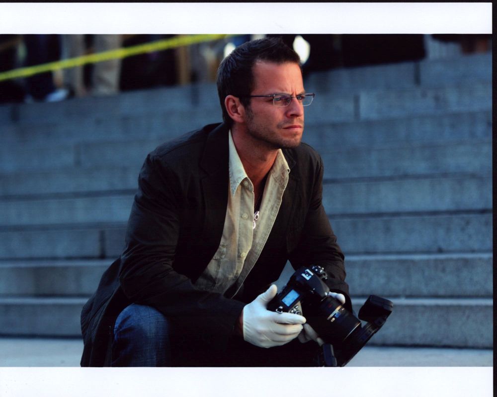 Carmine Giovinazzo on the set of CSI: NY, photo print in brown blazer with camera.