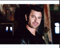 Diego Serrano leaning on a rusted wall in a leather jacket photo print.