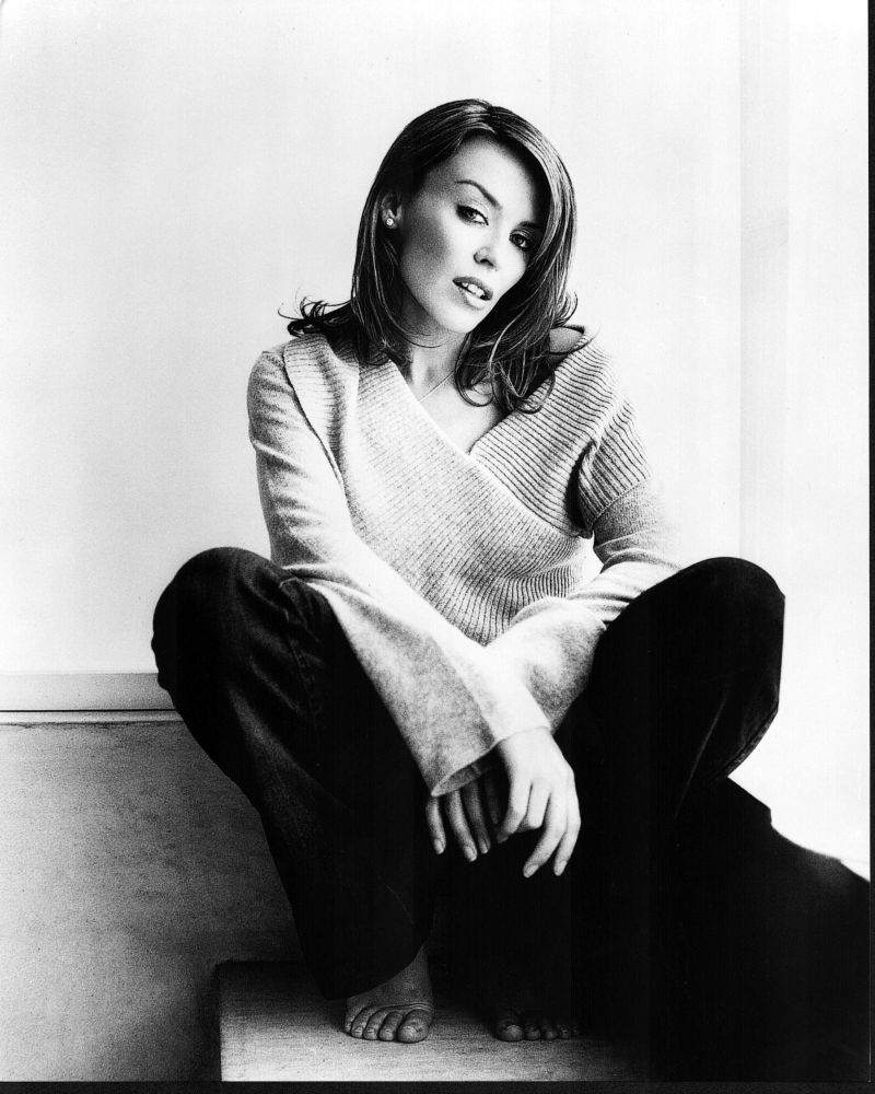 Kylie Minogue black and white photo print sitting in jeans and sweater.