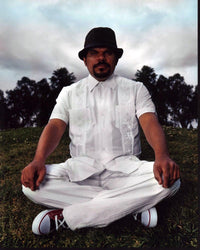 Luis Guzmán Sitting in Grass Photo Print showcasing a serene outdoor scene.