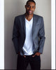 Jay Ellis in gray blazer photo print with hands in pockets.
