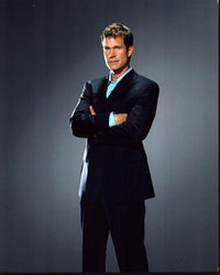 Dylan Walsh in a navy suit photo print, arms crossed, elegant portrait.