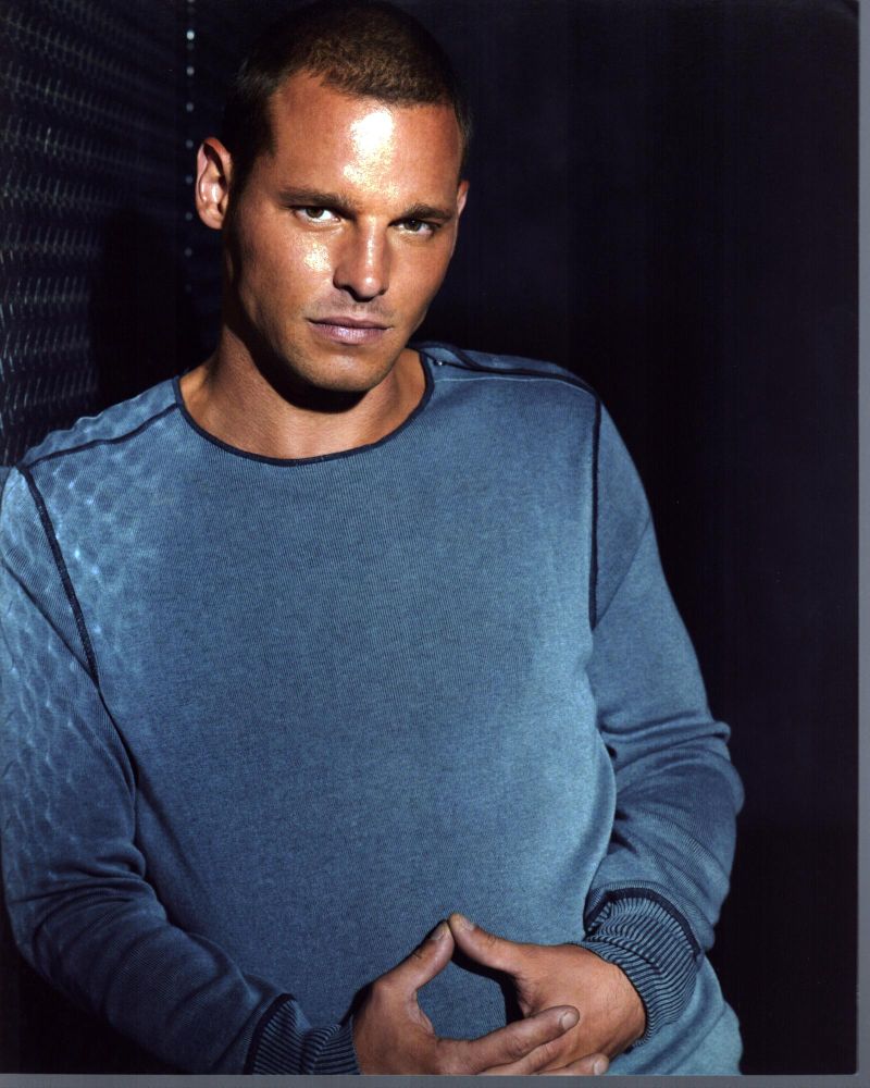 Justin Chambers leaning against a wall in a gray sweater photo print
