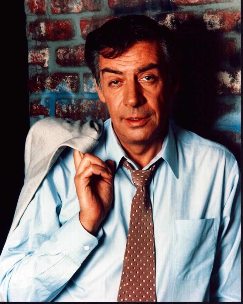 Jerry Orbach leaning on a brick wall with jacket over shoulder photo print