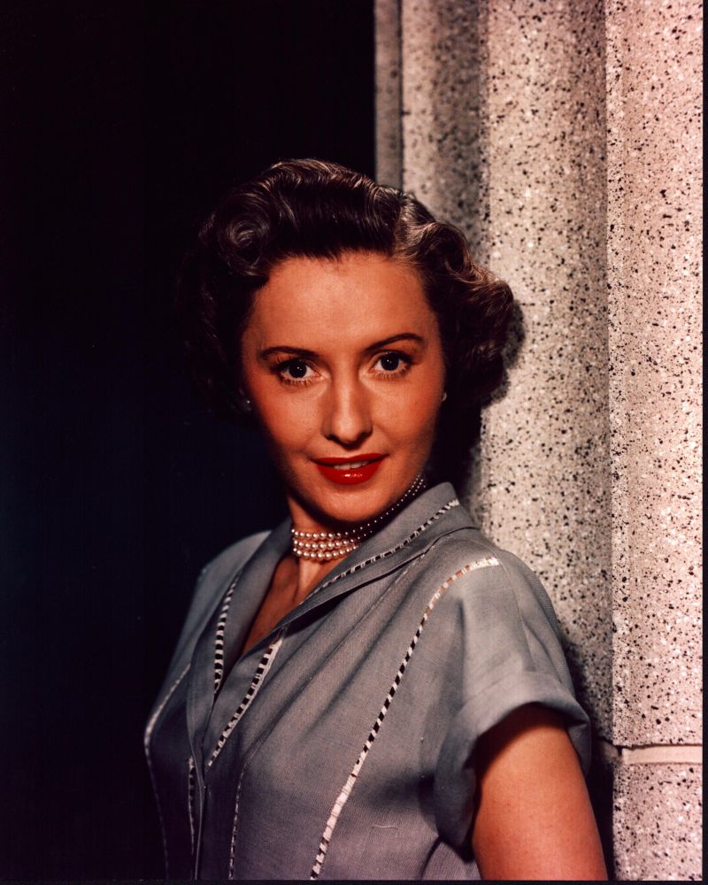 Barbara Stanwyck leaning on a stone pillar in a gray top photo print.