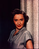 Barbara Stanwyck leaning on a stone pillar in a gray top photo print.