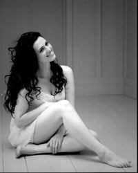 Black and white photo print of Katie McGrath sitting on the floor in a lace dress.