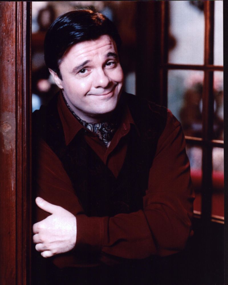 Nathan Lane photo print in red top and black vest, arms crossed.