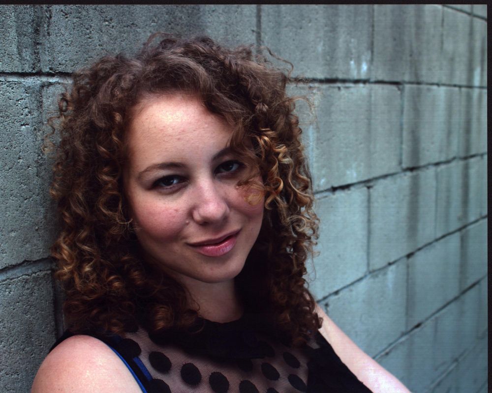 Anastasia Washington leaning against a wall in a black sheer top photo print