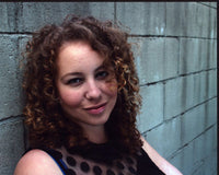 Anastasia Washington leaning against a wall in a black sheer top photo print