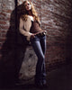 Holly Hunter leaning on a brick wall in jeans and a brown top photo print