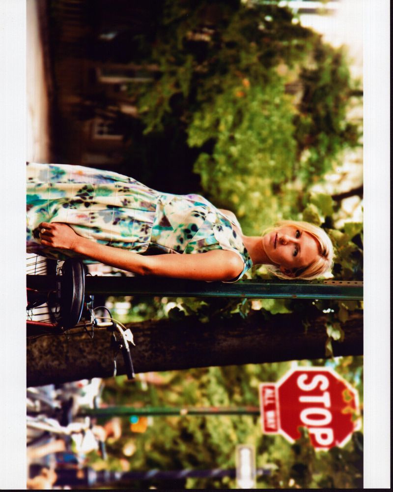 Mickey Sumner leaning against a street sign in a floral dress photo print