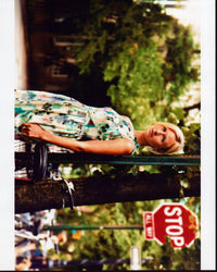 Mickey Sumner leaning against a street sign in a floral dress photo print