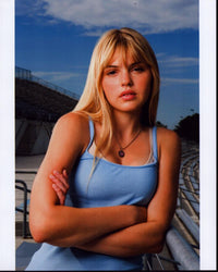 Aimee Teegarden in blue tank top photo print, arms crossed.