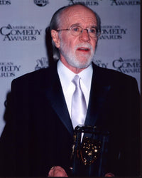 George Carlin photo print holding American Comedy Award in suit.