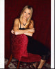 Molly Stanton in a black dress seated on a red chair - Photo Print
