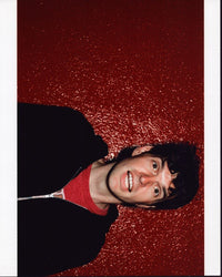 Timothy Simons photo print in a black sweatshirt against a red wall.