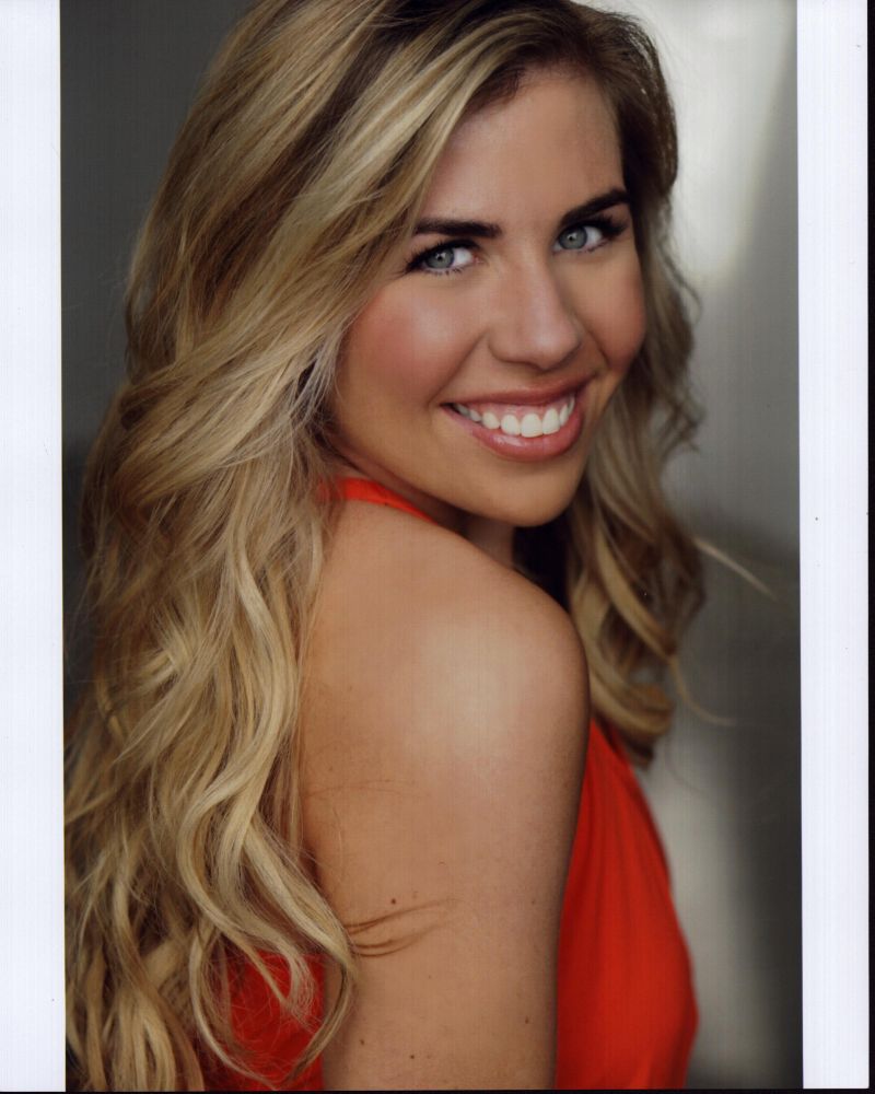 Sainty Nelsen looking over shoulder photo print in orange top.