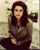 Neve Campbell seated in a tan blazer photo print.