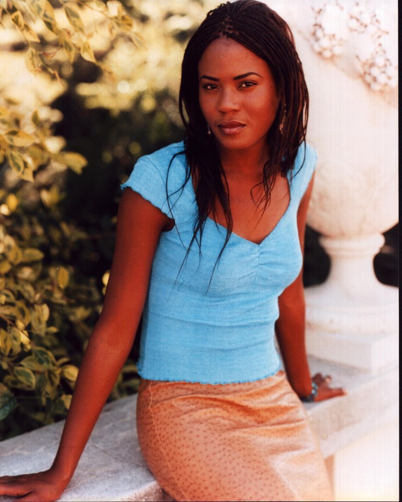 Tangi Miller sitting on a wall wearing a blue top - Photo Print
