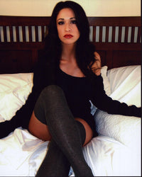 Photo print of Christina Bach sitting on bed in gray thigh highs.