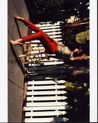 Aimee Garcia sitting on stool in front of a fence photo print.