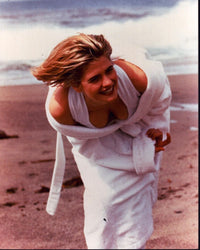 Kristy Swanson leaning forward on beach in white swimsuit and robe photo print