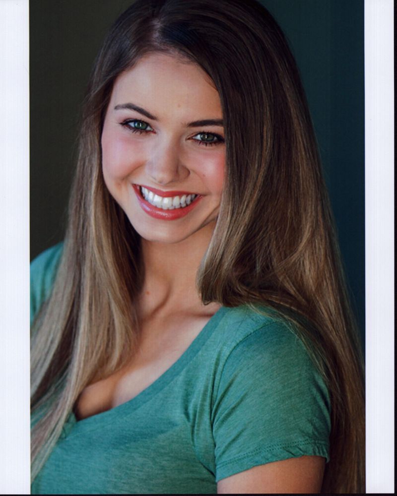 Ayla Kell smiling headshot photo print in a green shirt.