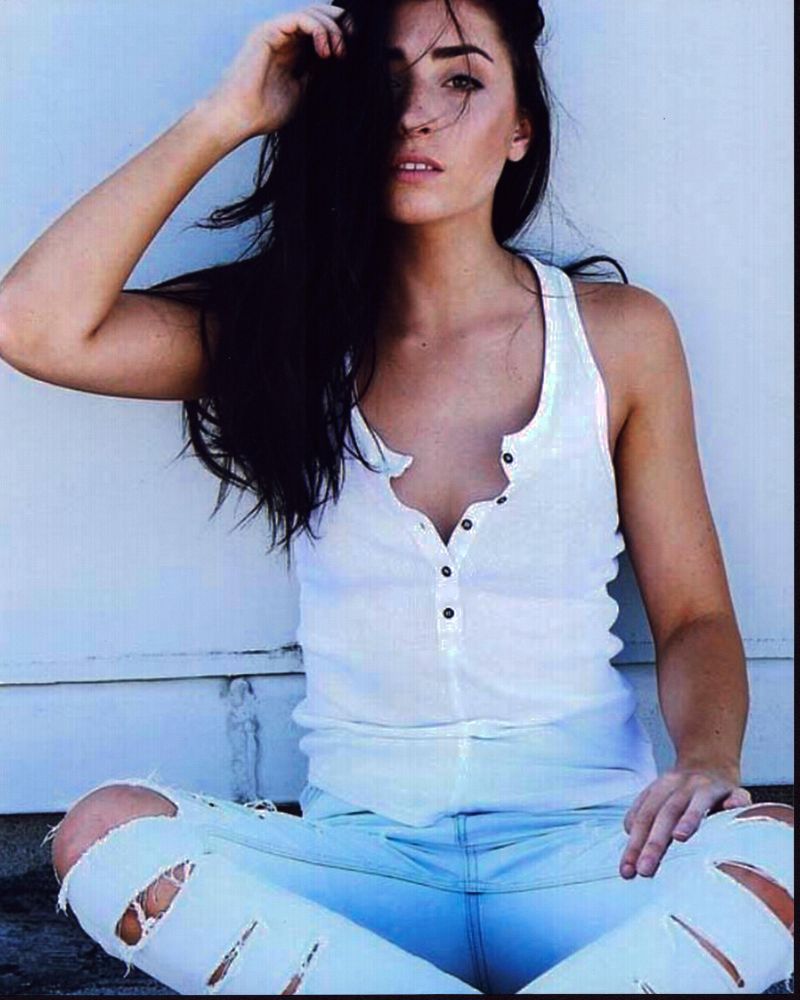 Lauren Elizabeth photo print sitting against wall in ripped jeans.