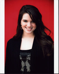 Katie Stevens headshot photo print featuring a black sweater on a red background.