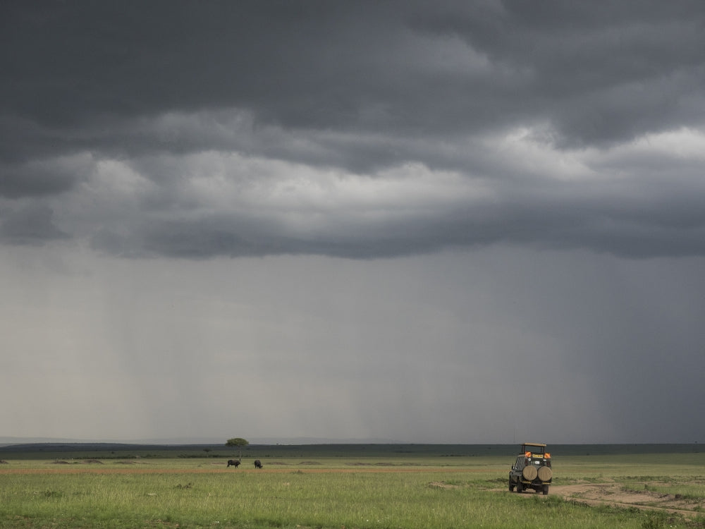 Storm clouds over a tourist vehicle in Maasai Mara National Reserve poster print