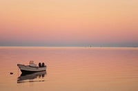 Pink sunrise over ocean with small boat poster print by Anthony Asael