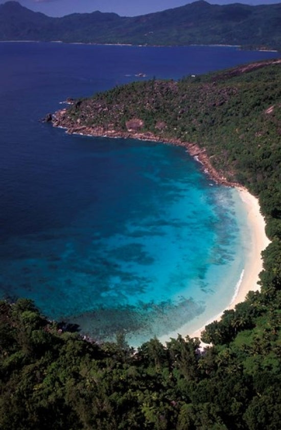 Aerial view of a tropical beach in Seychelles, showcasing clear waters and lush greenery.
