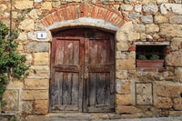 Monteriggioni stone wall with wooden door and geraniums poster print by Emily Wilson.
