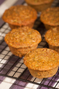 Zucchini muffins cooling on a wire rack above a striped tea towel poster print.