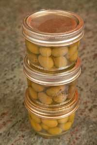 Three jars of home canned olives on a granite countertop in a kitchen poster print by Janet Horton