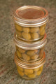 Three jars of home canned olives on a granite countertop in a kitchen poster print by Janet Horton