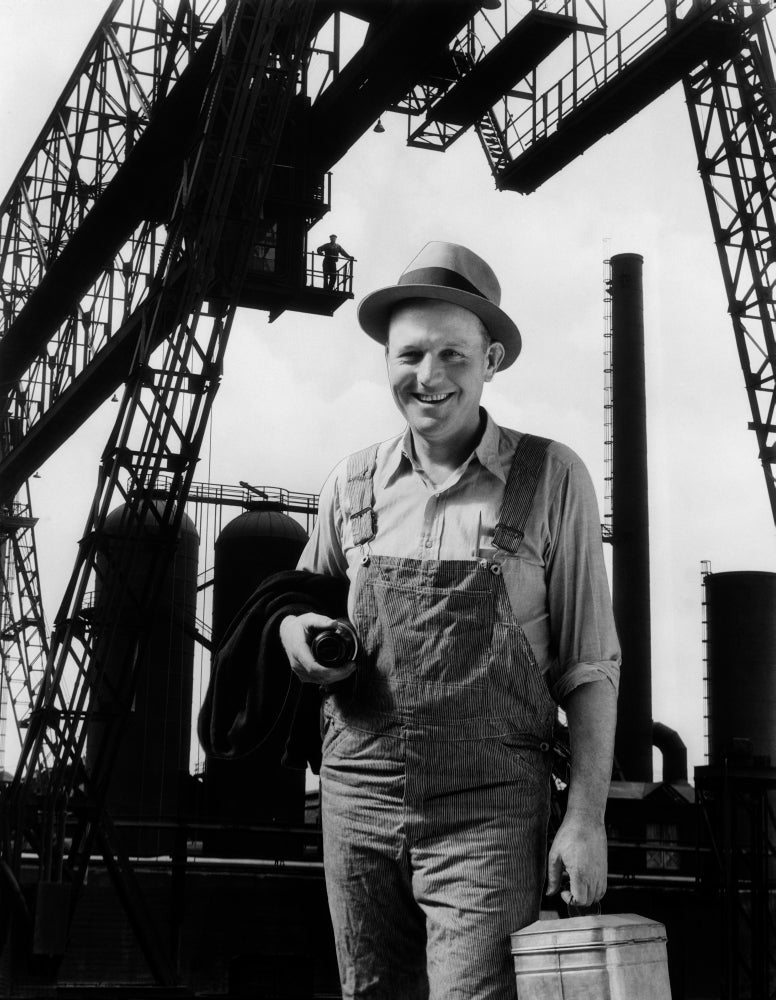 1930s print of a man worker with lunch pail in front of factory
