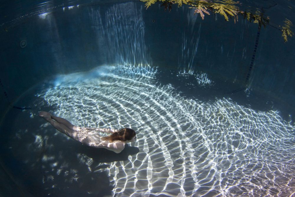 Underwater view of a woman swimming in a pool on Curacao by David Fleetham.
