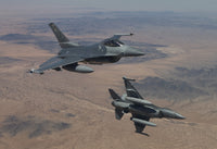 Two F-16 fighter jets from the 56th Fighter Wing flying over the Arizona desert.