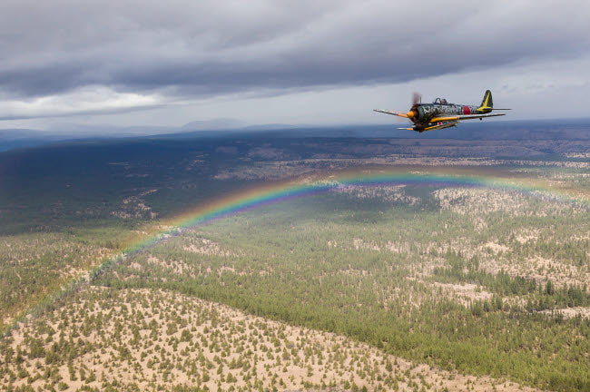 Japanese A6M Zero and Ki-43 Oscar flying in formation above a rainbow.