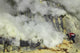 Miner breaking up sulfur deposits at Kawah Ijen Volcano in Indonesia poster print