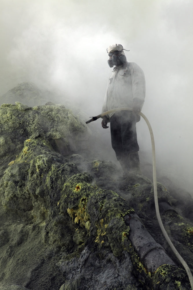 Miner waiting for water to cool piping on sulphur mine at Kawah Ijen volcano, Java, Indonesia poster print.
