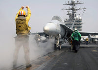 Aviation Boatswain's Mate directs an F/A-18C Hornet onto a steam-powered catapult - Poster Print