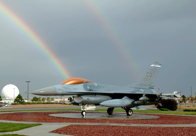 Rainbow Over F-16 Fighting Falcon Poster Print showcasing a vibrant rainbow and military aircraft.