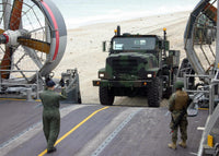 A Loadmaster guides a Marine 7-ton truck onto a Landing Craft, Air Cushioned poster print.