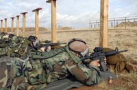Soldiers sighting M-4 rifles down range wearing protective gas masks poster.