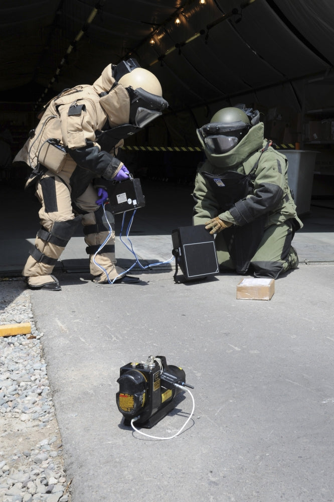 Soldiers dressed in bomb suits examining a suspicious package poster print.